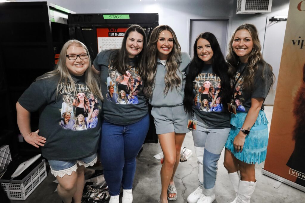 Carly posing with fans in the Carly Pearce shirts they had made