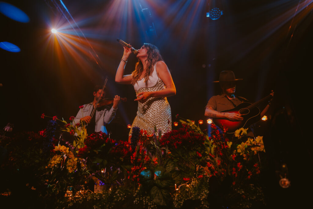 Carly Pearce performing on stage decorated with during her hummingbird world tour